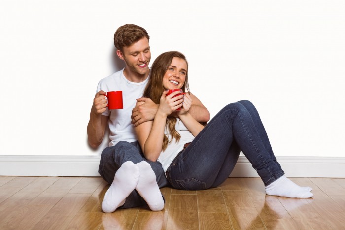 31891398 - cheerful young couple with coffee cups sitting on floor