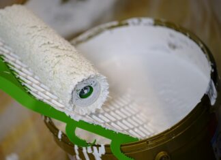 Remont coraz bliżej? Odwiedź hurtownię budowlaną Wrocław Czekoladowa OBI Wiadro z białą farbą i wałek malarski